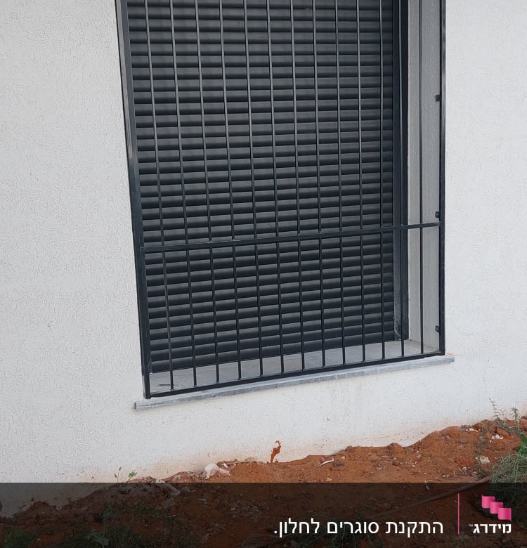 חלון עם סורגים שחורים על קיר לבן